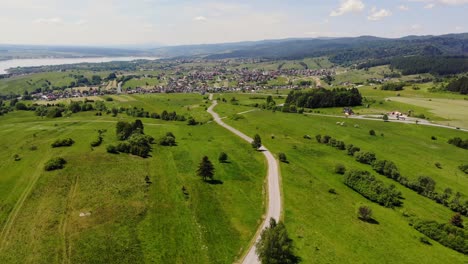 Road-through-pastoral-lands-of-summer-meadow-and-southern-Poland-village-panoramic-aerial