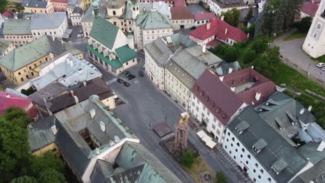 Tight-roads-in-old-european-middieval-town-with-square,-tall-plague-monument-and-church