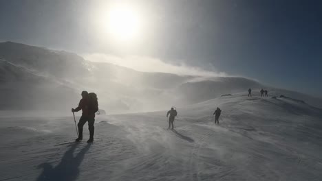 Gruppe-Von-Menschen,-Die-Bei-Sonne-Und-Schneesturm-Auf-Einem-Hohen-Berg-Ski-Fahren