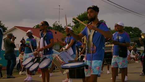 Medium-closeup-of-drummers-as-carnival-performers-walk-past-playing-at-sunset