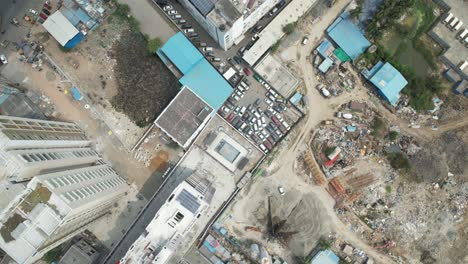 Aerial-video-of-an-abandoned-car-lot-filled-with-real-estate,-steel,-cement-blocks,-and-automobiles