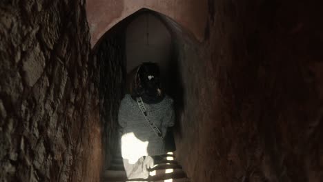 Una-Mujer-Explora-Un-Túnel-Subterráneo-Estrecho-Y-Poco-Iluminado,-Mirando-Hacia-Arriba,-Con-Una-Sensación-De-Descubrimiento.