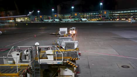 Geschäftige-Nacht-Am-Frankfurter-Flughafen-Mit-Fahrenden-Fahrzeugen,-Lufthansa-Logos-Im-Hintergrund,-Zeitraffer