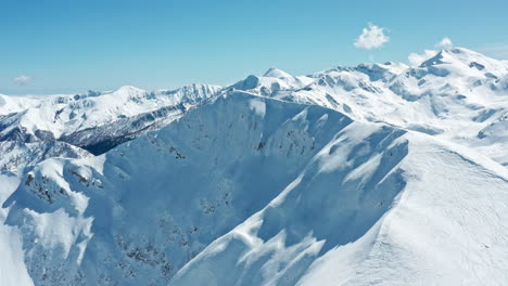 Schneebedeckte-Berggipfel-Unter-Einem-Klaren-Blauen-Himmel,-Luftaufnahme,-Majestätische-Winterlandschaft