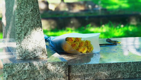 A-bouquet-of-yellow-flowers-on-a-marble-gravestone