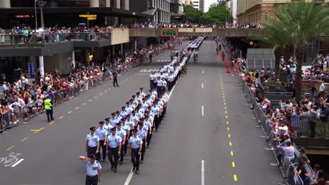 Airmen-and-women-from-Royal-Australian-Air-Force-march-uniformly-down-the-street,-honouring-those-who-served-during-wartime,-Anzac-Day-parade-with-cheering-crowds-alongside-the-street