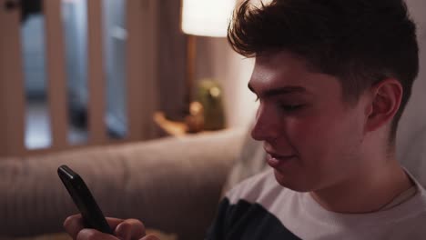 Junger-Mann-Nutzt-Soziale-Medien-Auf-Einem-Smartphone-In-Einem-Gemütlichen-Zuhause