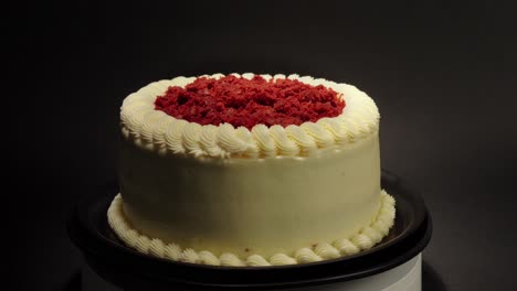 Red-velvet-cake-delicious-treat-tasty-in-a-turn-table-black-background-red-garnishing-on-top-cream-butter-outside