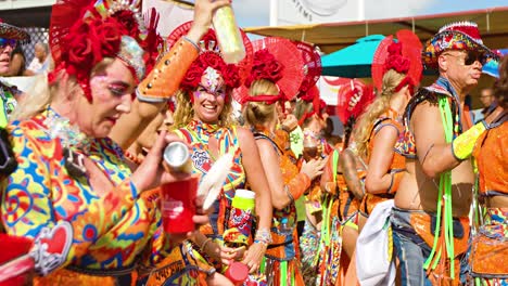 Women-dance-mixing-drinks-as-they-walk-along-Carnaval-parde-in-red-and-rainbow-bodysuits