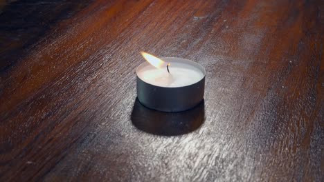 Burning-single-tea-light-candle-is-blown-out,-smoke-rises-from-wick