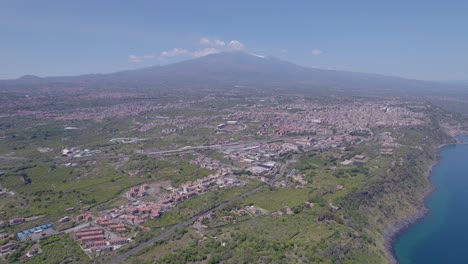 Aerial-establishing-shot-of-Acireale-city-in-Sicily,-Italy-with-a-stunning-view-of-the-Etna-volcano