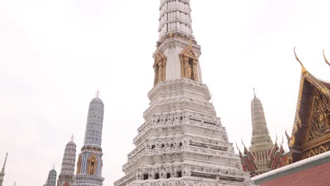 Mirando-Hacia-Las-Imponentes-Y-Detalladas-Agujas-De-Pagoda-En-Un-Complejo-De-Templos-Budistas-En-El-Casco-Antiguo-De-Rattanakosin-En-Bangkok,-Tailandia