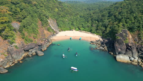Aerial-view-of-secret-beach-Butterfly-in-Goa,-India-with-rocky-bay-and-boats