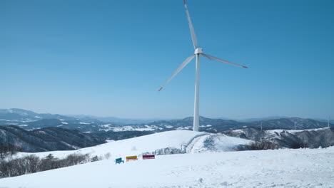 Riesige-Windturbine-Dreht-Sich-Im-Winter-Auf-Einem-Berggipfel-Vor-Blauem-Himmel-Auf-Der-Daegwallyeong-Sky-Ranch,-Daegwallyeong-Myeon,-Pyeongchang-Gun,-Gangwon-Do,-Südkorea
