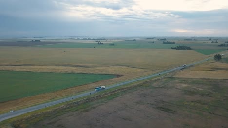 Aerial-shot-of-trucks-cruising-along-a-rural-road-amidst-fields