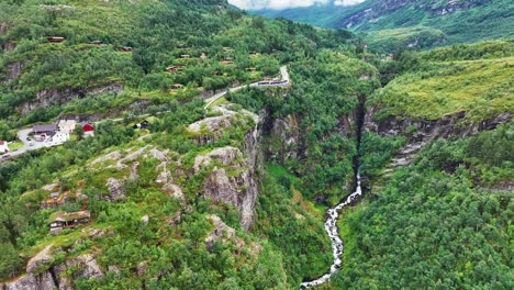 Vista-Aérea-De-Colinas-Verdes,-Cañón-Y-Ruta-Panorámica-Sobre-El-Pueblo-Y-El-Fiordo-De-Geiranger,-Noruega