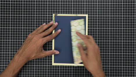 Hands-crafting-a-gift-card-with-gold-foil-on-a-gridded-cutting-mat,-overhead-view