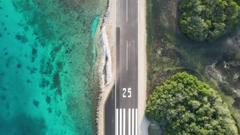 Gran-roque-airstrip-in-los-roques-with-turquoise-sea-and-lush-greenery,-aerial-view