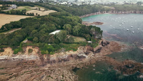 Downward-Arc-Aerial-of-a-Ruined-Castle-with-Large-White-Marquee-on-Ocean-Coastline