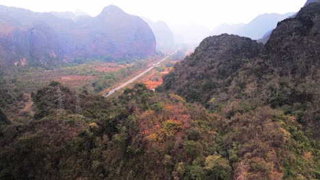 Smoggy-misty-karst-mountainous-landscape-with-supply-roar-cutting-through-during-dry-season-of-Northern-Laos