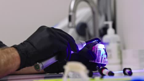 Dental-Technician-using-Ultraviolet-Light-to-put-Finishing-Touches-on-Fake-Teeth