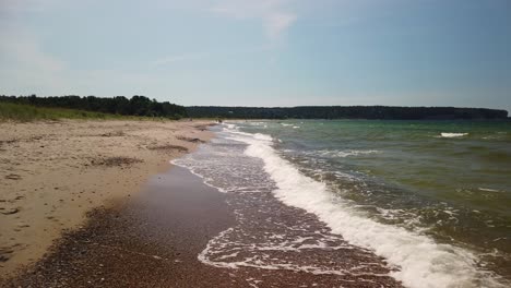 Ocean-waves-crash-with-foamy-white-wash-on-sandy-shore-of-Gotland,-Sweden