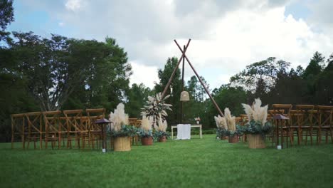 Outdoor-wedding-venue-arranged-with-many-wooden-chairs,-pampas-grass-decoration,-bohemian-style