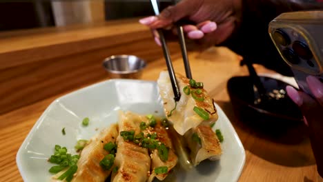 black-woman-using-chopsticks-to-pick-up-a-dumpling-from-a-plate