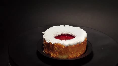 Mini-Tarta-De-Queso-Petite-Petit-Porción-Individual-Personal-En-Una-Mesa-Giratoria-Con-Un-Lazo-De-Fondo-Negro-Con-Crema-Encima-Y-Gelatina-De-Fresa-Y-Bayas