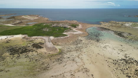 Vista-Aérea-Inclinada-Hacia-Adelante-De-Una-Playa-Con-Un-Barco-En-La-Arena-Durante-La-Marea-Baja.