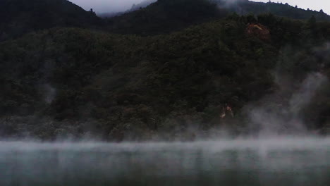 Zoom-in-on-steam-rising-from-geothermal-lake-in-volcanic-region,-New-Zealand,-North-Island