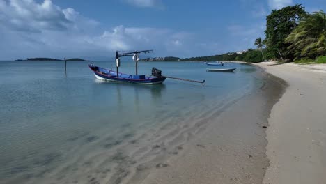 Tranquil-beach-scene-with-a-moored-boat-on-Koh-Samui's-clear-waters,-sunny-day