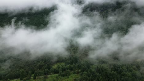 green-forest-on-a-mountain-between-many-clouds,-norway,-nature,-drone