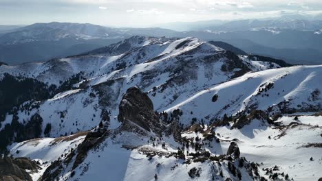 Schneebedeckte-Ciucas-Berge-Unter-Blauem-Himmel,-Mit-Zerklüftetem-Gelände,-Das-Im-Licht-Des-Späten-Nachmittags-Schatten-Wirft,-Weitwinkelaufnahme
