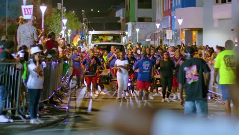 Pan-down-to-dancing-group-of-performers-drumming-in-middle-of-street