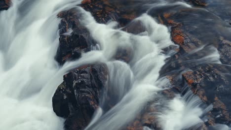 Un-Poderoso-Flujo-De-Aguas-Bravas-Sobre-Las-Rocas-Oscuras-Astilladas-En-El-Video-De-Larga-Exposición