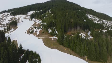 Aerial-shot-of-Saalbach-Hinterglemm-ski-resort-in-Austria-with-melting-snow,-showing-the-transition-from-winter-to-spring,-ascending-view