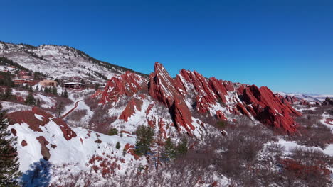 March-winter-morning-after-snowfall-stunning-Roxborough-State-Park-Colorado-aerial-drone-landscape-sharp-jagged-dramatic-red-rock-formations-Denver-foothills-front-range-blue-sky-downward-motion