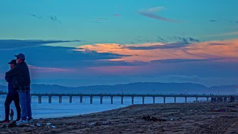 Couple-relaxing-watching-sunset-dirty-Manhattan-Beach-USA-time-lapse