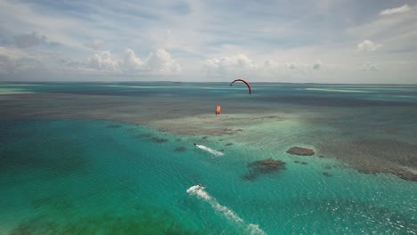Kitesurfers-gliding-over-clear-blue-waters-at-cayo-vapor-in-los-roques,-aerial-view