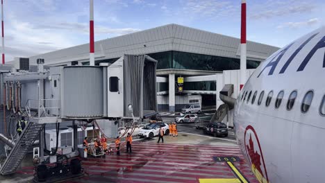 Ground-operations-for-Air-Canada-aircraft-at-airport-terminal-gate-and-aerobridge-or-jetway-detached-with-operators-at-work-on-tarmac