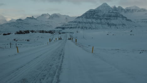 Blick-Auf-Die-Isländische-Asphaltstraße,-Die-Bei-Sonnenuntergang-Mit-Schnee-Und-Eis-Bedeckt-Ist