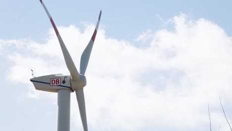 Close-up-of-a-DB-branded-wind-turbine-against-a-cloudy-sky,-green-energy-concept