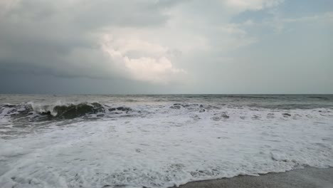 Slow-Motion-of-Waves-Crashing-onto-Sandy-Beach,-Overcast-Summer-Day