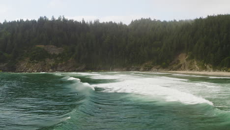 Low-flyover-above-surfers-paddling-through-Pacific-Ocean-waves-on-Oregon-Coast