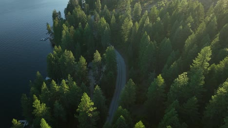 Overhead-drone-shot-of-a-country-road-winding-along-the-shore-of-Spirit-Lake,-Idaho