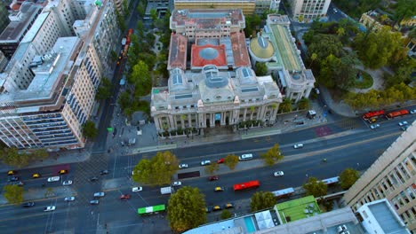 Aerial-drone-fly-above-National-library-central-building-at-Santiago-de-Chile-city-government-landmark,-historical-architecture,-cultural-travel-destination-cars-drive-by-avenue,-traffic