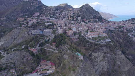 Aerial-establishing-shot-of-Taormina,-Sicily,-Italy-a-south-side-of-the-city-on-the-volcano