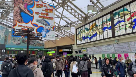 Belebter-Bahnhof-In-Japan-Mit-Pendlern-Und-Bunten-Werbetafeln,-Schildern-über-Der-Decke