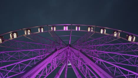 Purple-ferris-wheel-wide-shot,-ground-level-up-shot-in-night-time